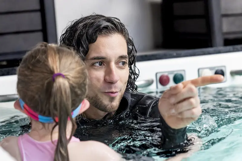 A SwimTec coach in the Endless Pool points out the next skill to a young swimmer beside him