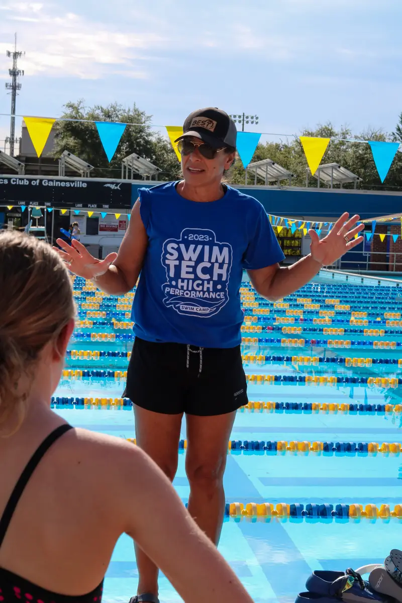 A SwimTec camp coach talks with swimmers on a 50-metre pool deck